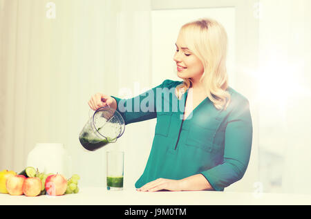 glückliche Frau mit Mixer Krug gießen Saft zu Hause Stockfoto