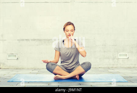 Frau macht Yoga Meditation in Lotus Pose auf Matte Stockfoto