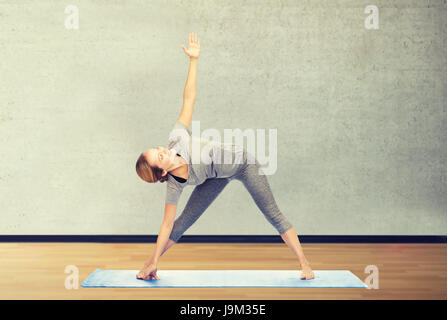 Frau macht Yoga Dreieck-Pose auf Matte Stockfoto