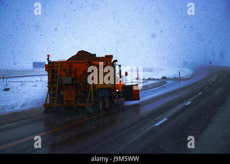 Ein gelb/Orange Schneepflug geparkt in der Median der Interstate in Wyoming, USA. Stockfoto