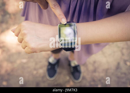 Vogelperspektive Blick auf weibliche Zeigefinger Taste auf smart-Uhr. Stockfoto