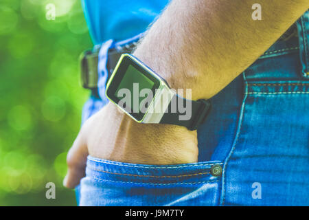 Hautnah-Shooting der männlichen Hand in Jeans-Tasche und tragen Smartwatch mit leeren Bildschirm. Stockfoto
