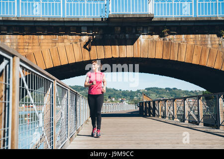 Attraktive und glücklich mittlere gealterte Frau Joggen im Freien an einem sonnigen Tag Stockfoto