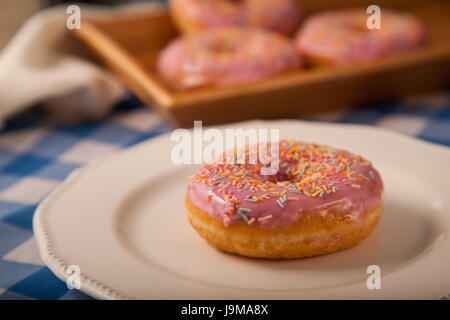 Rosa Donut auf einem Teller Stockfoto