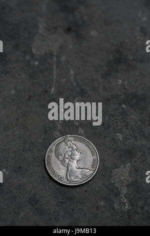 Nahaufnahme der australischen 20 Cent (1966) Münze auf dunklen konkreten Hintergrund. Buch Cover oder Plakat Vorlage mit einem Leerzeichen kopieren. Stockfoto