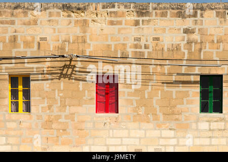 Drei bunte Fenster lackiert, gelb, rot und Grün in einem alten Steingebäude in Marsaxlokk Malta Stockfoto