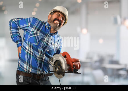 Senior-hispanischen Arbeitnehmer leiden Rückenverletzung Gebäudeinneren Stockfoto