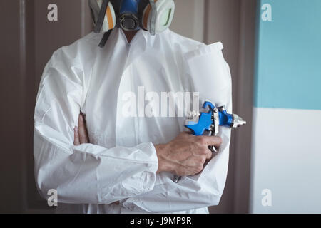 Mittleren Bereich des Mitarbeiters halten Farbspritzpistole und mit Gasmaske auf dem Fahrrad workshop Stockfoto