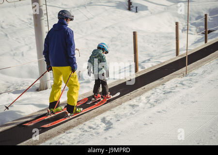 Vater und Tochter, Skifahren im Winter auf Förderband Stockfoto