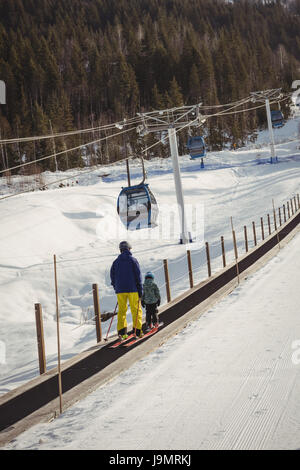 Vater und Tochter, Skifahren im Winter auf Förderband Stockfoto