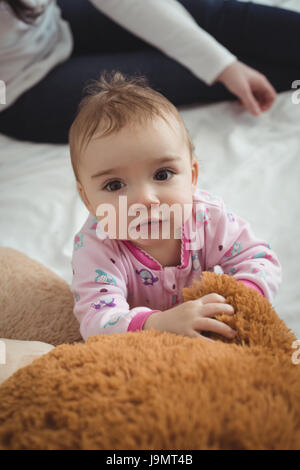 Niedliche Baby Spiel mit Teddybär im Bett im Schlafzimmer Stockfoto