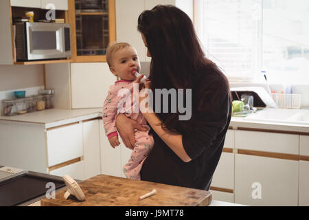 Mutter füttert Medizin, Baby in Küche zu Hause Stockfoto