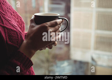 Nahaufnahme von Frau hält eine Kaffeetasse in der Nähe des Fensters Stockfoto
