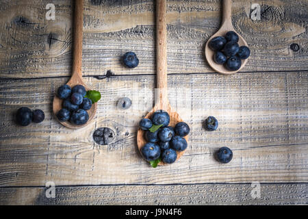 Heidelbeeren auf Holzlöffel auf hölzernen Hintergrund von oben Stockfoto
