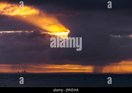 Von Rottnest Island nach Perth über den Ozean mit dramatischen Sonnenstrahlen durch die Wolken platzen. Stockfoto