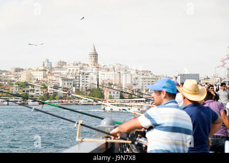 Männer Angeln am Galata-Brücke, mit der Galata-Turm und Beyoğlu im Hintergrund sichtbar. Istanbul, Türkei. Stockfoto