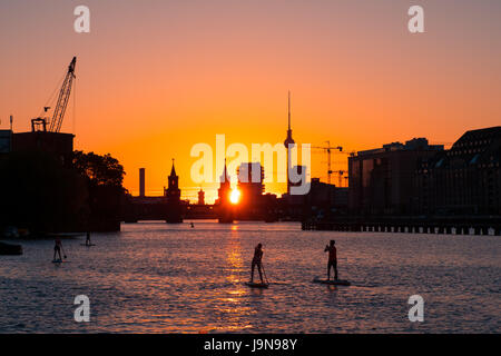 Personen an Bord Paddel / aufstehen Paddler an Spree in Berlin - Sonnenuntergang Himmelshintergrund, Oberbaumbrücke und Fernsehturm Stockfoto