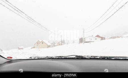 Ein Winter-Straße einen Tag mit schweren Schneefall und fast keine Sicht voraus. Bild durch eine Windschutzscheibe. Straumsbukta, Kvaløya, Tromsø, Norwegen. Stockfoto