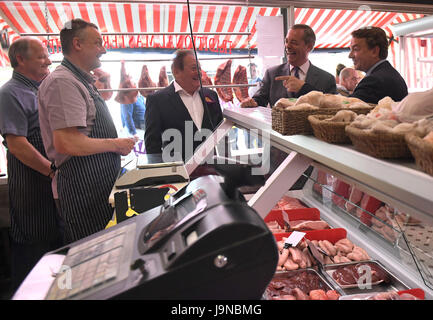 Ehemalige Ukip Führer Nigel Farage (zweiter von rechts) und die lokalen Parteianwärter Tim Aker (rechts) sprechen Sie mit ein paar der Metzger beim allgemeinen Wahlen Kampagne Besuch Ockendon, Essex. Stockfoto