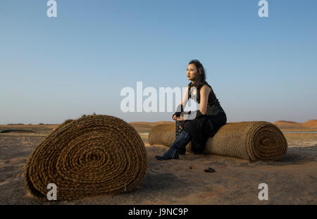 junge Frau ruht auf einem alten Teppich in einer Wüste in der Nähe von Dubai Stockfoto