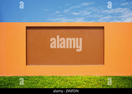 schöne orange Wand, moderne Zement Zaun mit Wiese und blauer Himmel am hellen Tag Stockfoto