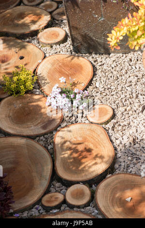 Schneiden Sie Protokolle als Sprungbrett in eine Blume Garten zeigen. UK Stockfoto