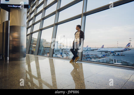 Porträt von ein attraktiver junger Mann zu Fuß und mit Blick auf Handy Stockfoto