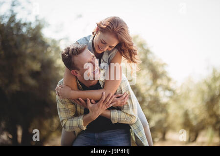 Niedrigen Winkel Blick lächelnder Mann, die Frau am Olivenfarm Huckepack Stockfoto