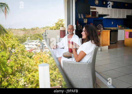 Paar, sitzen auf dem Balkon mit Blick auf den Yachthafen von Nuevo Vallarta, Nayarit, Mexiko Stockfoto