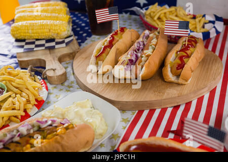 Nahaufnahme von Burger und Maiskolben auf Holztisch mit 4. Juli Thema Stockfoto