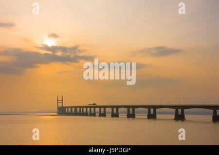 Der Prinz von Wales Brücke (Zweite Severn Crossing) während einer diesigen Sonnenuntergang über den Severn Estuary von Severn Strand, Gloucestershire, England gesehen. Stockfoto