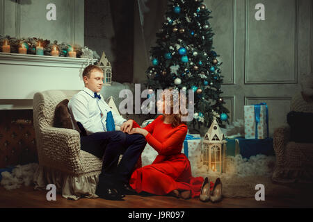 Familienzimmer in der Nähe von einem Weihnachtsbaum. Am Abend Kerzen leuchten im Zimmer herum, unter dem Baum sind Geschenke. Stockfoto