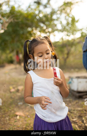 Eine Mädchen schmeckt frisch geerntete Honig auf ihrer Farm in Léon Abteilung, Nicaragua. Stockfoto