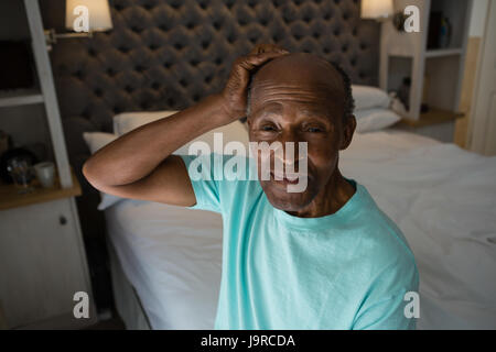 Porträt von lächelnden senior Mann sitzt am Bett zu Hause Stockfoto