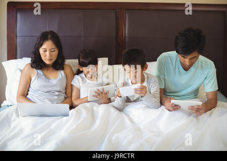 Familie mit Hilfe von elektronischen Geräten im Schlafzimmer zu Hause Stockfoto