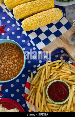 Nahaufnahme von Pommes Frites und Maiskolben auf Holztisch mit 4. Juli Thema Stockfoto