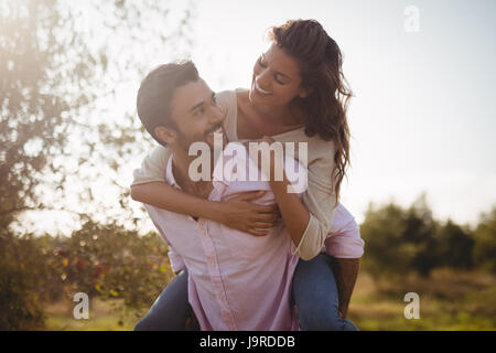 Lächelnde junge Frau am Bauernhof im sonnigen Tag Huckepack Stockfoto