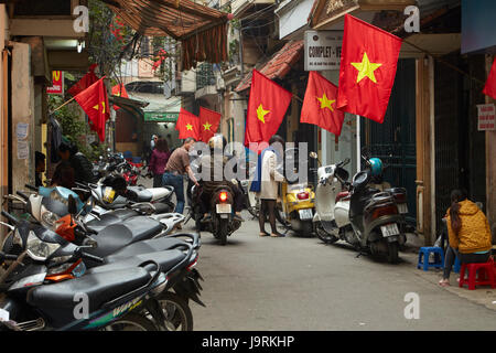Motorräder in und vietnamesische Flaggen in belebten Altstadt, Hanoi, Vietnam Stockfoto