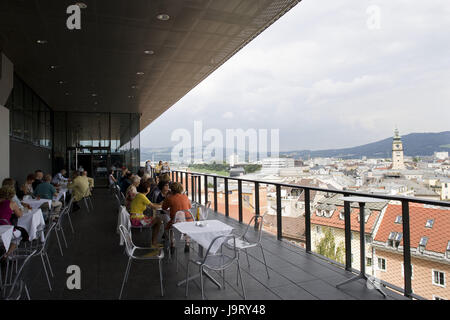 Österreich, Oberösterreich, Linz, Café, Person, Landeshauptstadt, Kulturmetropole, Industriestadt, Architektur, Struktur, Fassade, Gebäude, Häuser, Ort von Interesse, Reiseziel, Himmel, Wolken, Museum, draußen, Touristen, Blick auf die Stadt, Terrasse, Tische, Stühle, Ansicht, Stadt, Dächer, Turm, Balkon, Schloss Museum, Museumscafé, Übersicht, Stockfoto