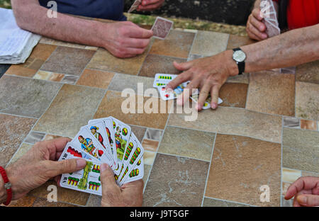 Ältere Gentleman Spielkarten an einem gemeinsamen Tisch im Park. Stockfoto