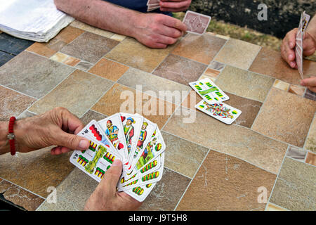 Ältere Gentleman Spielkarten an einem gemeinsamen Tisch im Park. Stockfoto