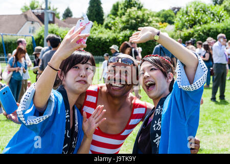 England, Coxheath. Custard Pie-Weltmeisterschaft. Zwei japanische Frauen posieren mit Mann von einem anderen Team für ein Selbstporträt. Alle Lächeln, sehr glücklich. Stockfoto