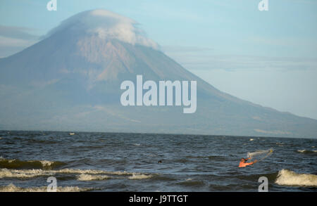 Ein Fischer wirft ein Netz ins Wasser des Nicaragua-See im Schatten des Vulkans El Ometepe. Stockfoto