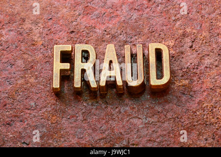 Betrug-Wort, das aus metallischen Lettern auf rotem rostige Oberfläche Stockfoto