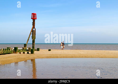 Ein paar Walking am Strand bei Ebbe an der North Norfolk Resort von mundesley-on-sea, Norfolk, England, Vereinigtes Königreich. Stockfoto