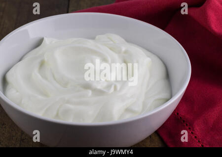 Naturjoghurt in weiße Keramikschale mit roten Serviette Stockfoto