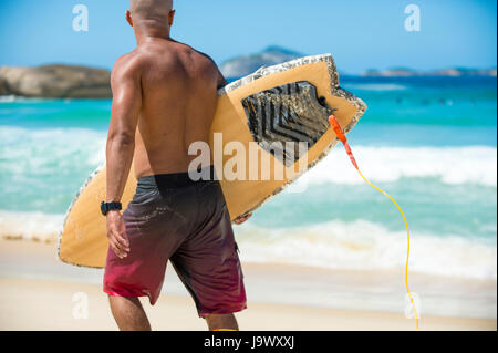 RIO DE JANEIRO - 9. Februar 2017: Brasilianische Surfer zu Fuß mit seinem Surfbrett entlang des Ufers am Arpoador Beach, die beliebte Surf-Break in Rio de Ja Stockfoto