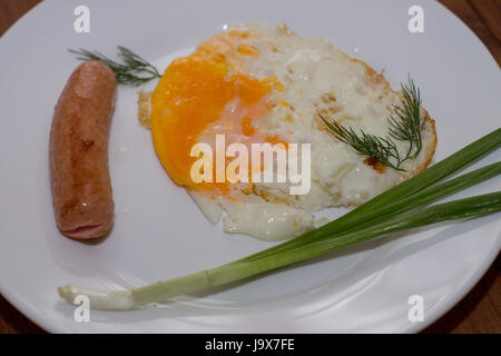 Frühstück auf einer Platte. Spiegeleier mit Würstchen und grünen Zwiebeln. Stockfoto