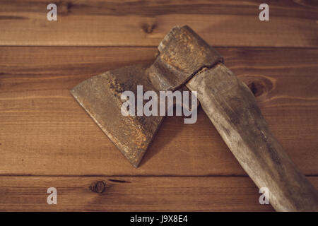 Alte rostige Axt auf einem hölzernen Hintergrund. Stockfoto