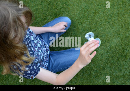 Ein Kind spielt mit einem drehenden Fidget Spinner im Garten Stockfoto